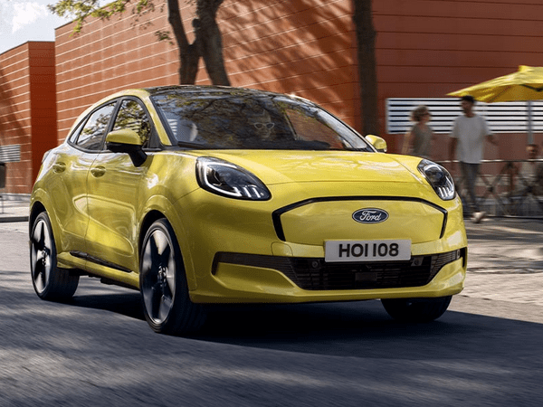 Gelber Ford SUV steht auf einer Stadtstraße mit modernen Gebäuden im Hintergrund. Menschen sind im Hintergrund sichtbar.