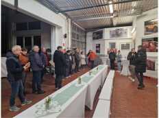 Eine Gruppe von Menschen steht in einem Raum mit Tischen und Ausstellungen, während eine Person spricht.