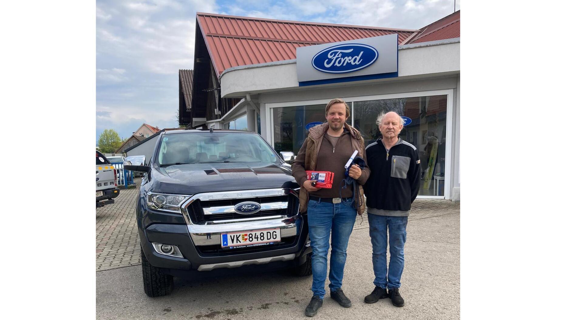 Zwei Männer stehen neben einem schwarzen Ford Pickup vor einem Ford Autohaus.