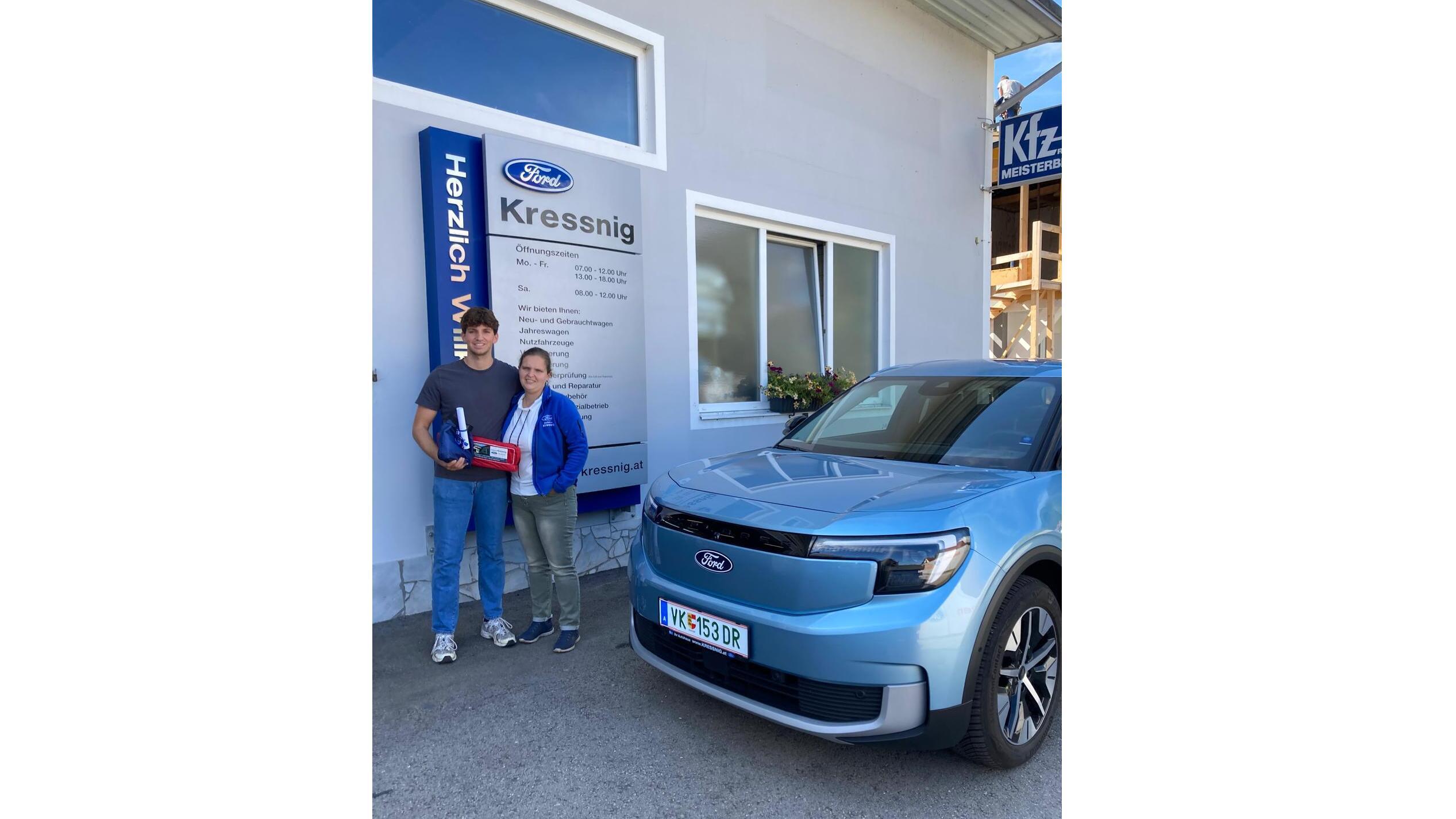 Zwei Personen stehen vor einem blauen Ford-Auto und einem Kfz-Service-Schild in Kressnig.