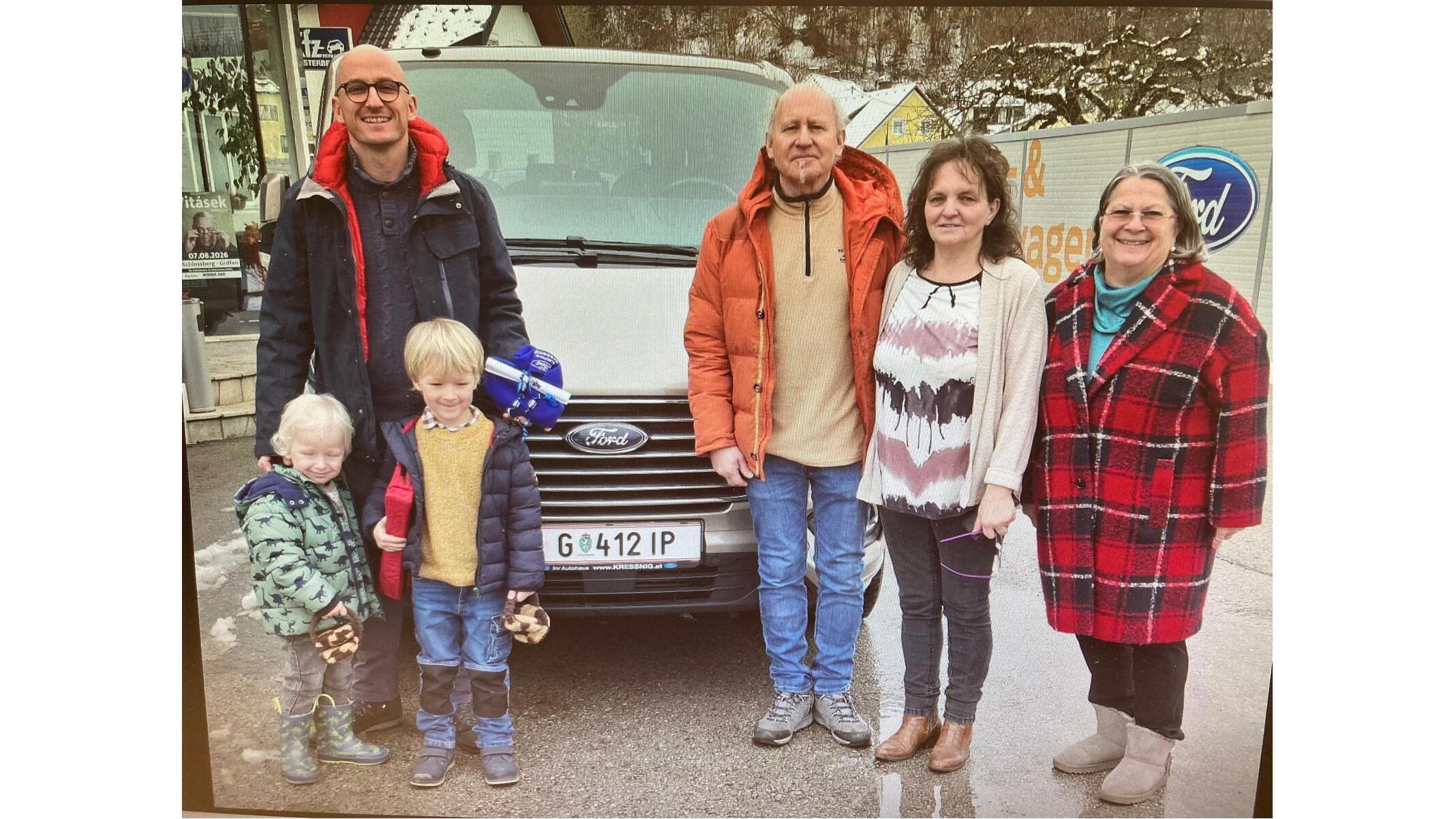 Eine Gruppe von fünf Personen steht vor einem Ford-Fahrzeug, glücklich zusammen in der Natur.