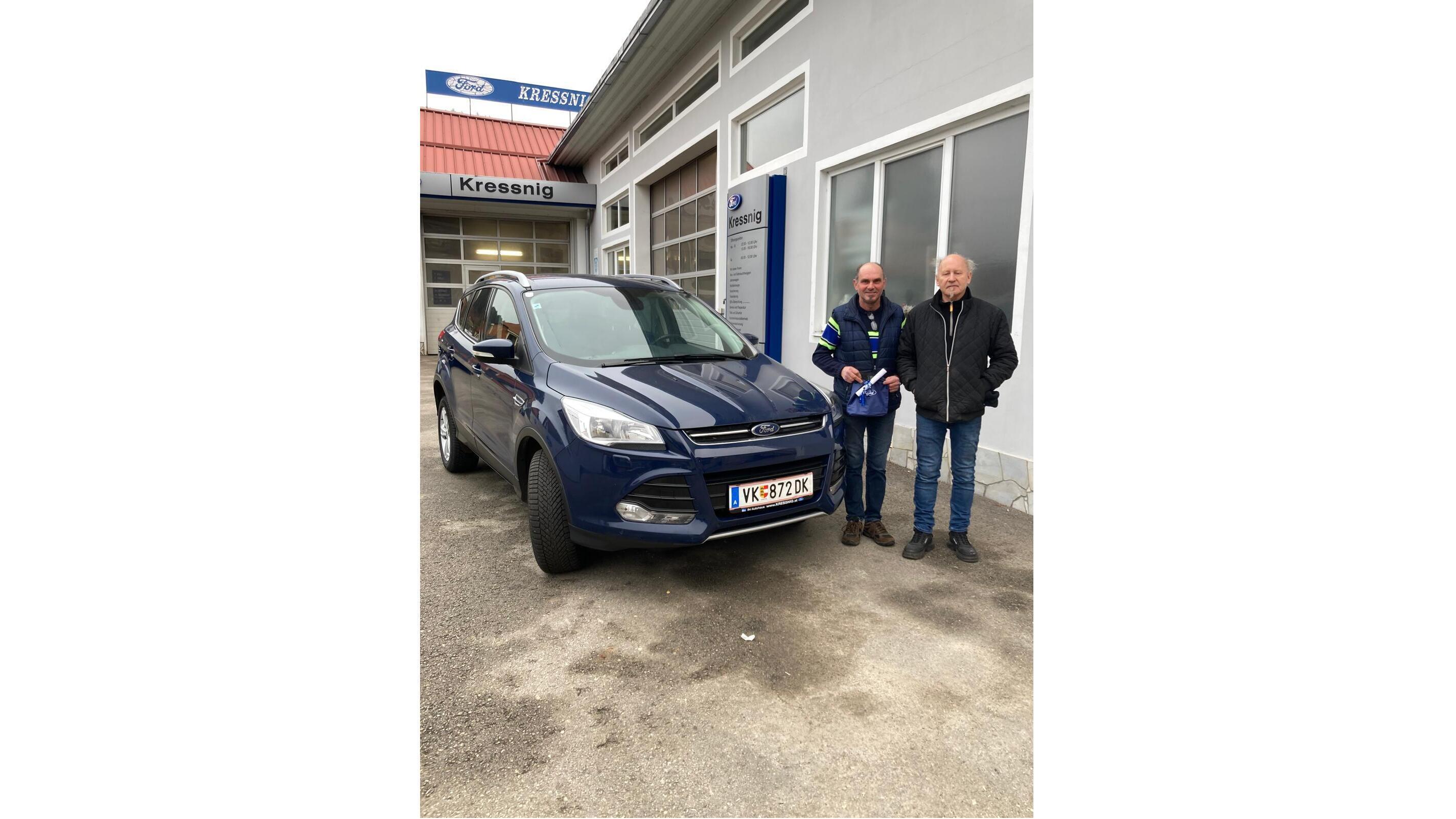 Zwei Männer stehen neben einem blauen Ford Kugas vor einem Autohaus in Österreich.