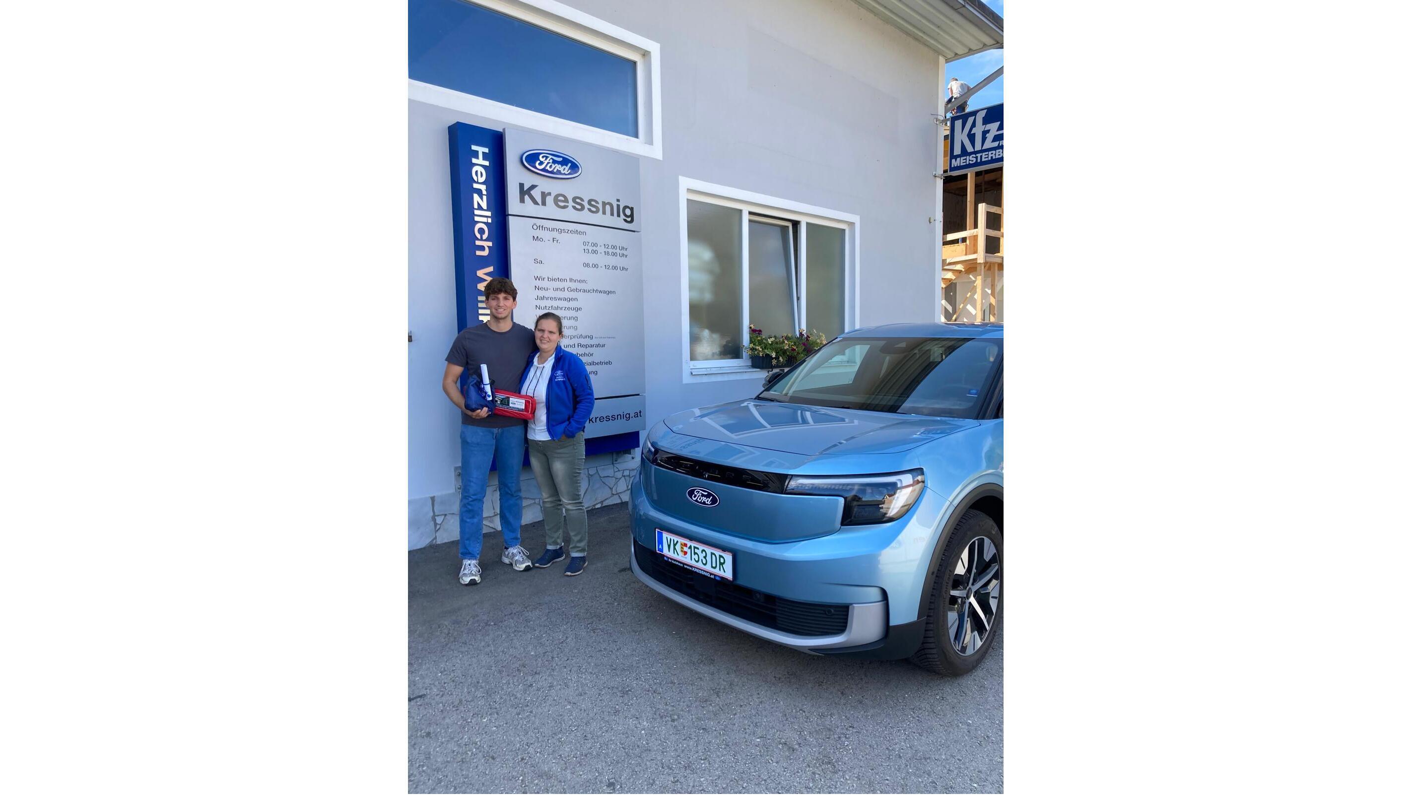 Zwei Personen posieren vor einem Ford-Auto bei der Kressnig-Filiale mit einem Schild im Hintergrund.
