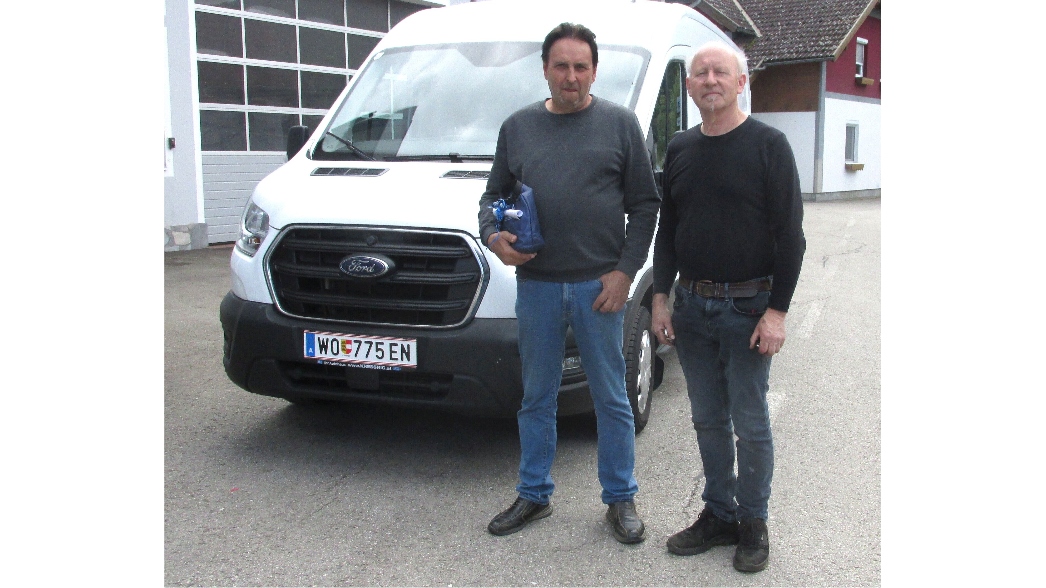 Zwei Männer stehen vor einem weißen Ford Transporter, am Straßenrand, lächelnd und entspannt.