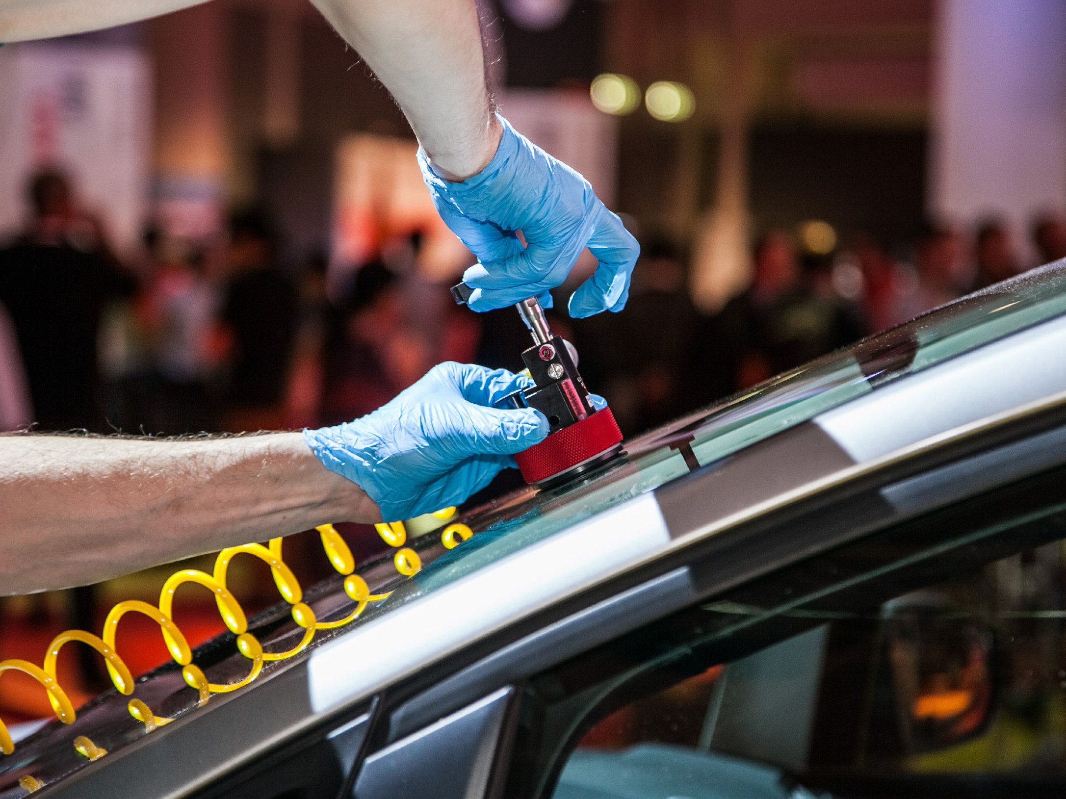 Ein Techniker, der mit Handschuhen an einem Autodach arbeitet, um eine Reparatur durchzuführen.