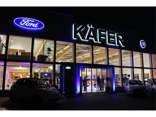 Moderne Ford-Käfer Autohäuser mit beleuchteten Schildern und Autos bei Nacht.