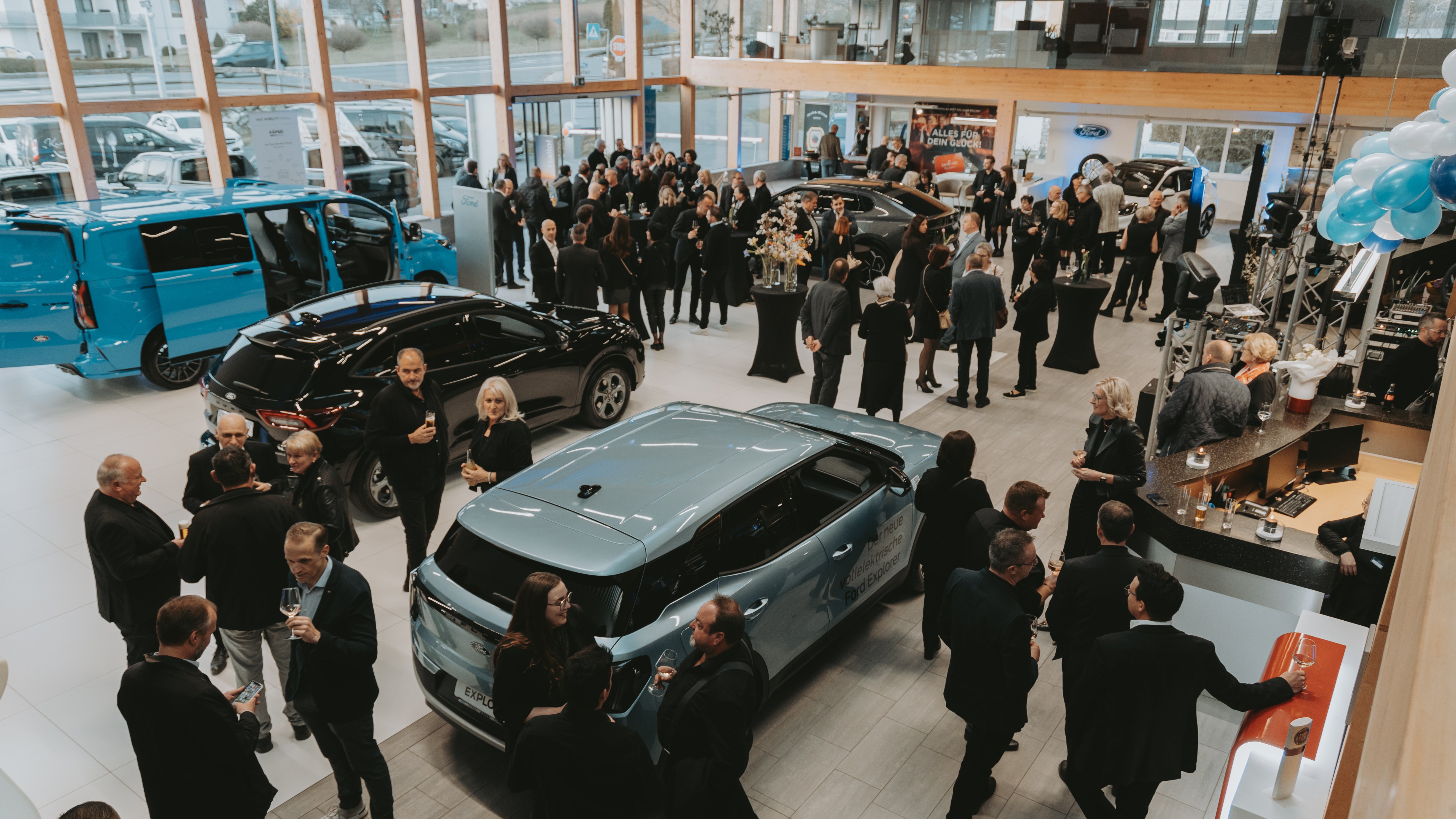 Eröffnungsveranstaltung eines Autohauses mit Gästen, modernen Fahrzeugen und festlicher Atmosphäre.