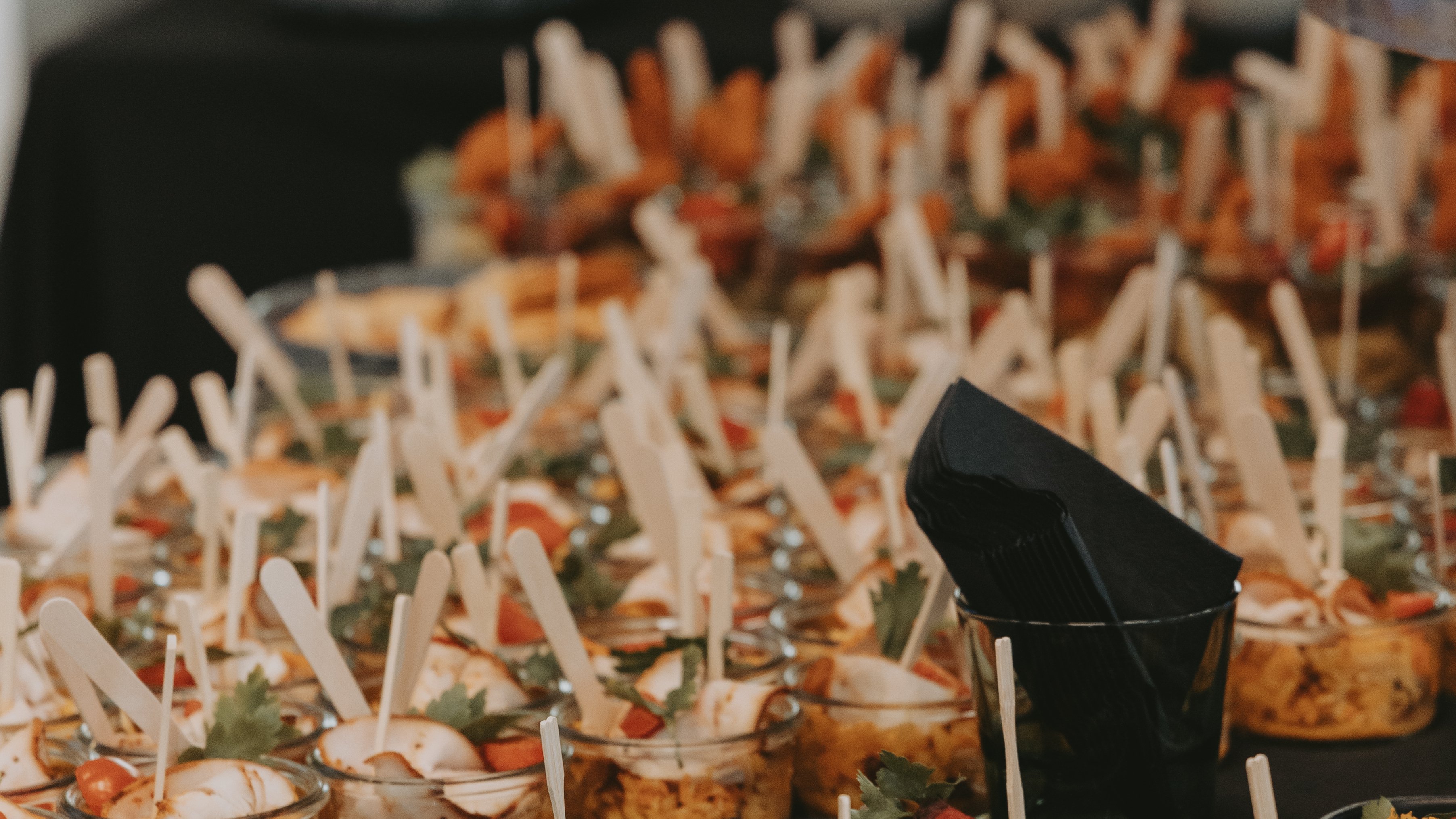 Ein Buffet mit vielen kleinen Gläsern voller speisen, dekoriert mit Holzstäbchen und frischen Zutaten.