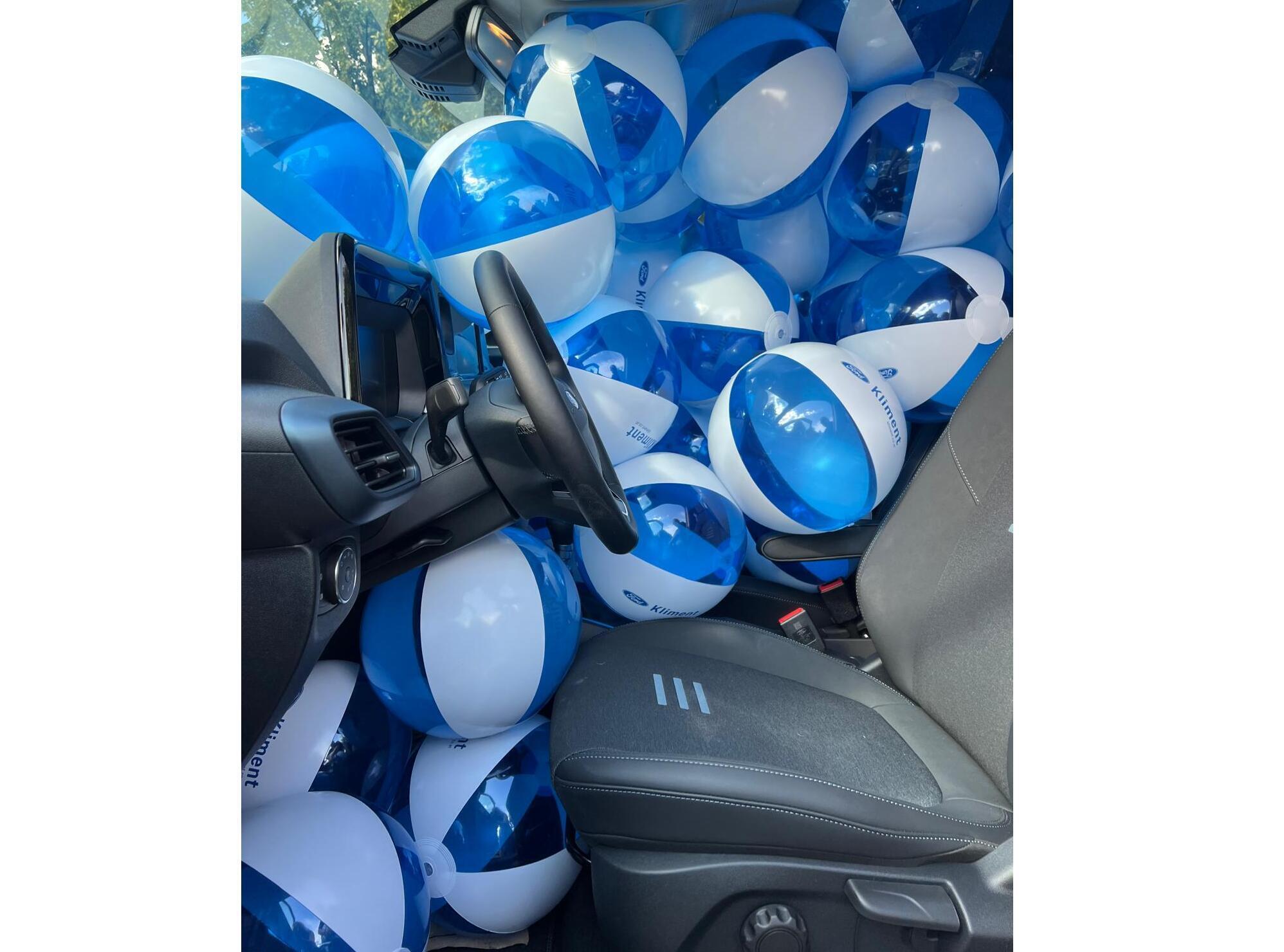 Ein Auto, das mit blauen und weißen Strandbällen gefüllt ist, nur das Lenkrad ist sichtbar.